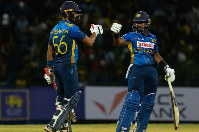 Two Sri Lankan cricketers fist bump during an ODI match, celebrating their partnership under floodlights.